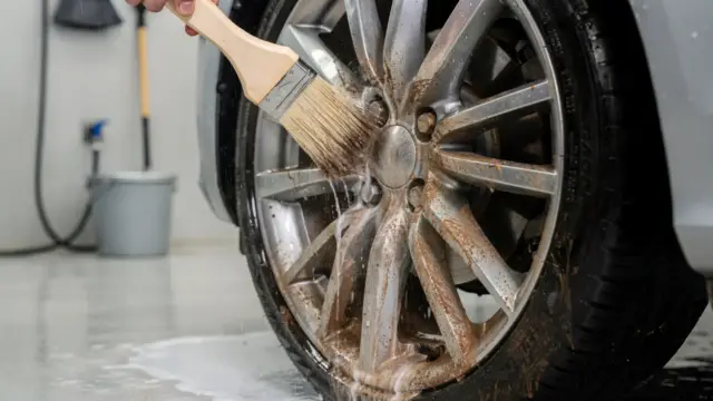 Felge beim Vorwaschen mit Bürste und Wasser zur Entfernung von Bremsstaub vor der Autowäsche