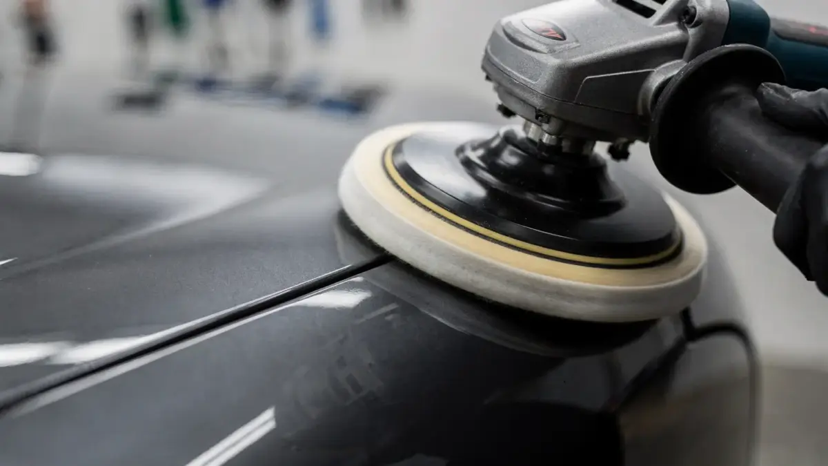 Hände beim Polieren eines Autos mit Poliermaschine: Anpresskraft als Thema des Artikels