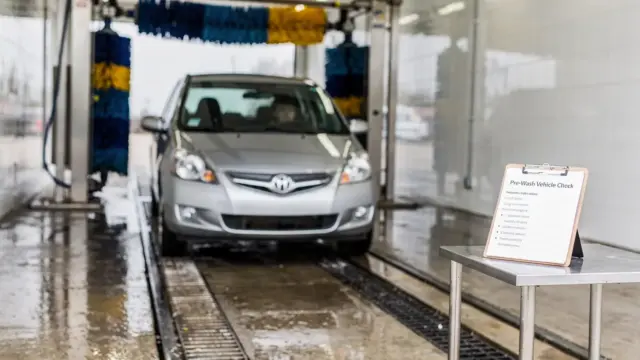 Auto vor der Waschanlage mit Checkliste zur Schadenmeldung vor dem Waschgang